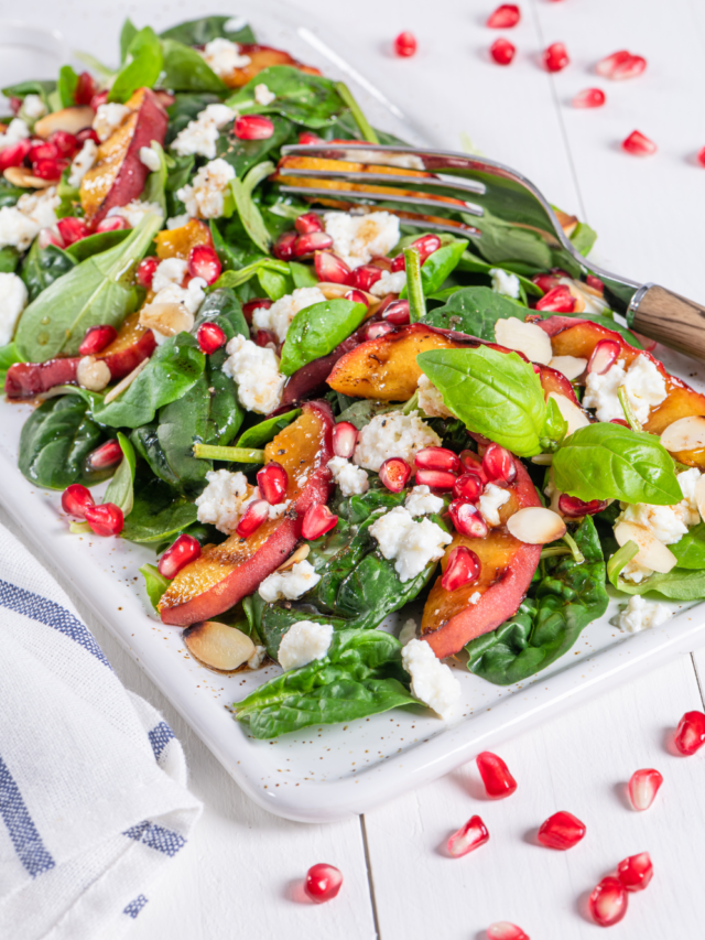 A Fresh Pomegranate Feta Salad recipe with grilled peaches and spinach leaves. A side dish or breakfast meal drizzled with a honey dressing.