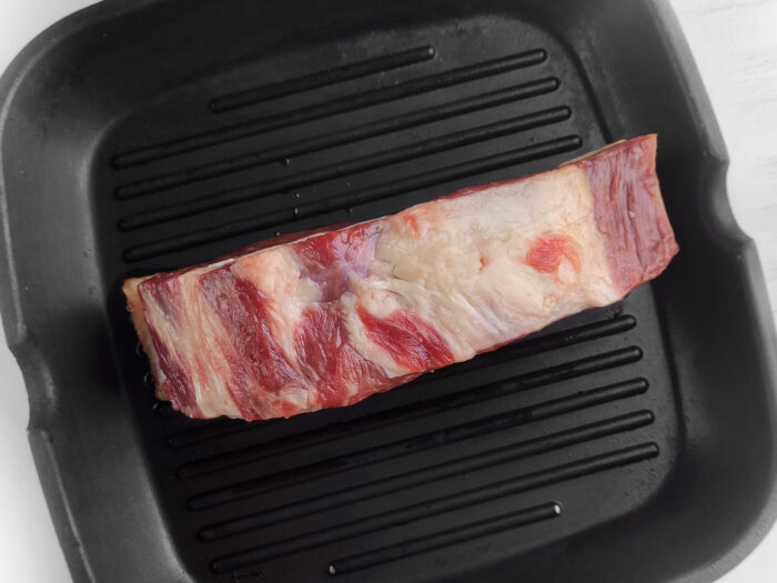 searing the side fat, Best Grilled Ribeye Steak recipe in a cast iron pan. Easy stove top idea for dinner or lunch as the steak is grilled with butter, garlic.