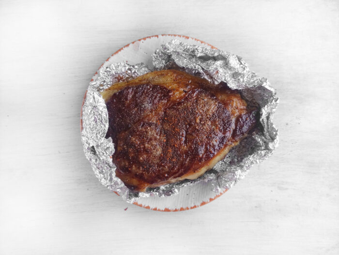 resting in foil to keep warm before serving, Best Grilled Ribeye Steak recipe in a cast iron pan. Easy stove top idea for dinner or lunch as the steak is grilled with butter, garlic.