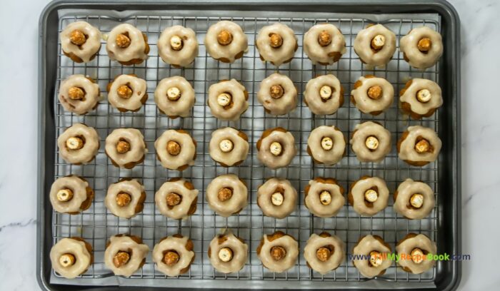 inserting a pretzel, These Mini Pumpkin Bundt Cakes recipe are spicy and made from scratch. An easy bake,  with vanilla butter icing, makes a moist dessert.