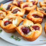 The most delicious mini Cranberry Brie Puff Pastry Bites appetizer recipe idea. Simple to make ahead for a sweet and savory holiday snack.