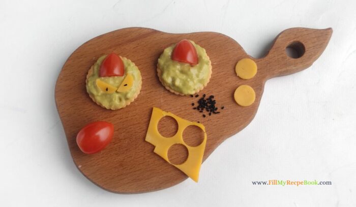 cherry tomato and cheese with avocado spread on a cracker for an appetizer or snack for the Christmas holiday season.