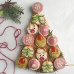 Simple Christmas Cracker Appetizers recipe ideas for snacks and treats. Crackers garnished with cream cheese, salami, cucumber, cherry tomato.