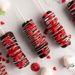 Simple Marshmallow Pops for Valentine's idea for kids. Stack three marshmallows on a stick, dip in chocolate, and add heart sprinkles.