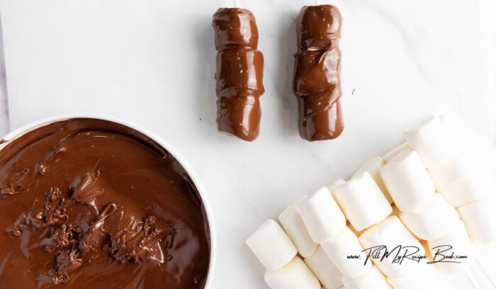 Simple Marshmallow Pops for Valentine's idea for kids. Stack three marshmallows on a stick, dip in chocolate, and add heart sprinkles.