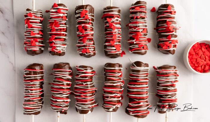 Simple Marshmallow Pops for Valentine's idea for kids. Stack three marshmallows on a stick, dip in chocolate, and add heart sprinkles.