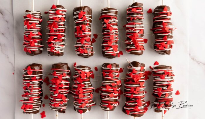 Simple Marshmallow Pops for Valentine's idea for kids. Stack three marshmallows on a stick, dip in chocolate, and add heart sprinkles.