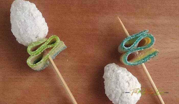 coconut candy unwrapped to for another flower on the skewer with greenery. Learn how to make a Valentine's Day DIY Candy Bouquet idea to create for a special someone. A beautiful packaged gift to suit anyone.