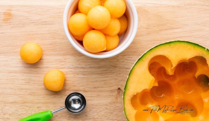 Using a melon baller, scoop out round balls of cantaloupe. Ensure the balls are uniform in size for a pleasing presentation.