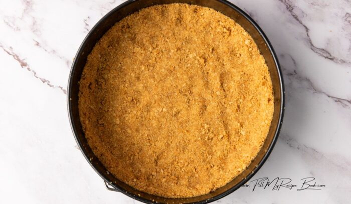 biscuit base made with graham crackers or tennis biscuits, butter and fine sugar. line the cake pan and bake.