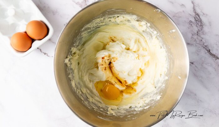 In a large bowl, beat the cream cheese and sugar together until smooth and creamy. Add the vanilla extract and mix until combined. Add the eggs one at a time, beating well after each addition.