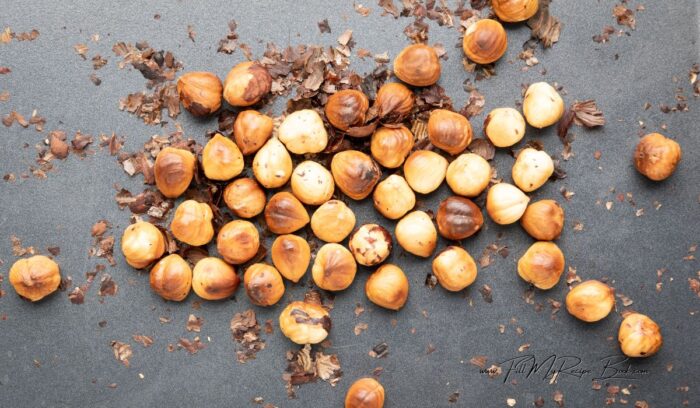 Place the hazelnuts in the oven and roast them for approximately 5 minutes. Then allow them to cool off and use your hands to remove the skin.