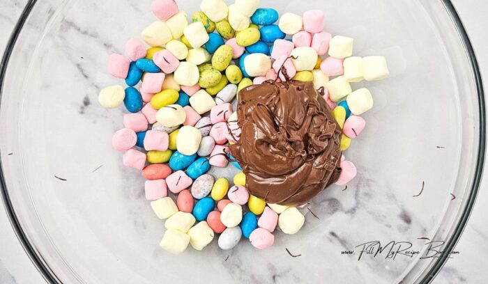 Add the marshmallows and ¾ cup Robin Eggs to a large bowl. Stir the milk chocolate into the candy marshmallow mixture, then fold the white chocolate in.