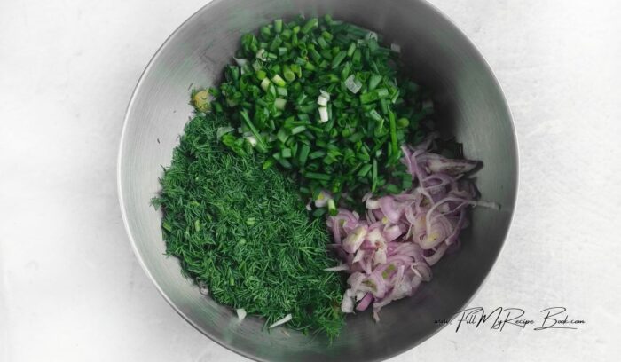 Cut the pickles into small cubes and place in a salad bowl. Rinse the dill and spring onions in cool water, dry on a towel and finely chop. Peel the purple onion and chop it into thin rings. Add the ingredients to a bowl.